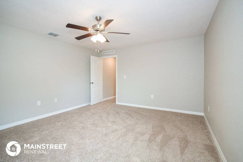 the spacious living room with carpet and ceiling fan
