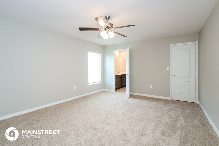 the spacious living room with carpet and ceiling fan