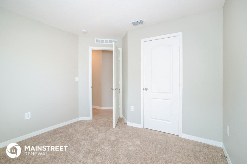 a bedroom with a white door and a hallway to a closet