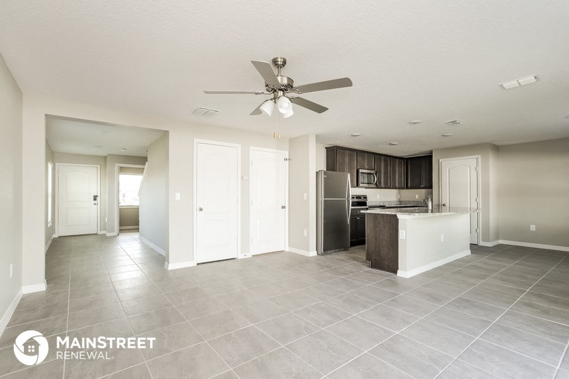 the kitchen and living room of an apartment with a ceiling fan