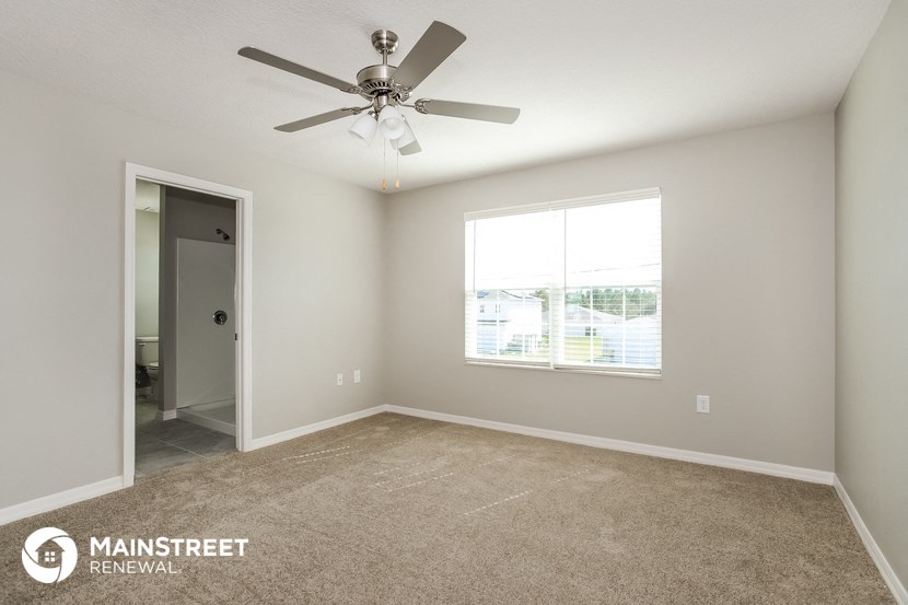 the master bedroom has carpeted floors and a ceiling fan