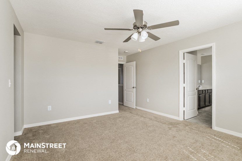 a spacious living room with carpet and a ceiling fan
