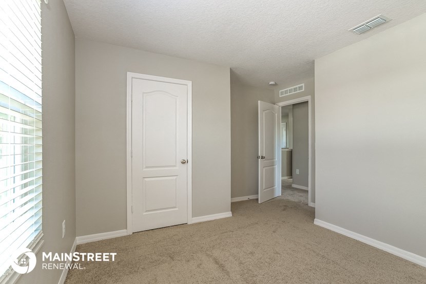 the living room of an apartment with a carpeted floor and a door to the