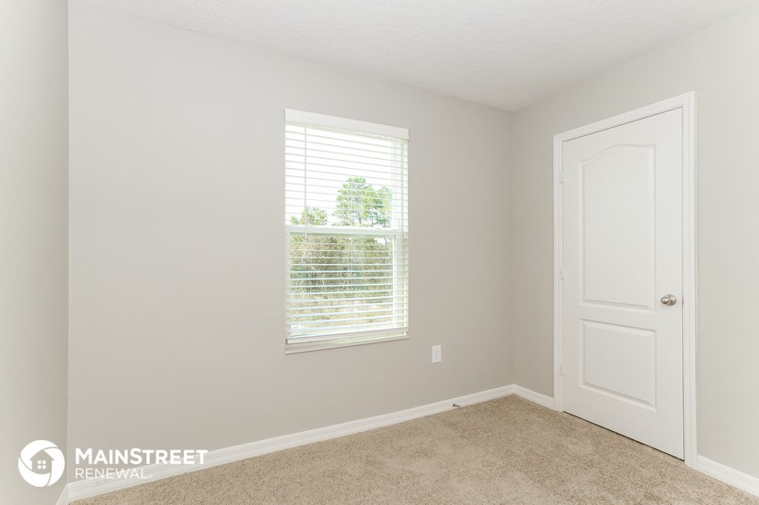a bedroom with a window and a door and a carpeted floor