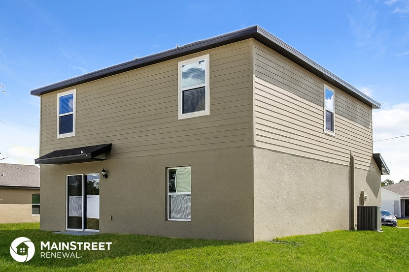 a beige house with tan siding and a green lawn