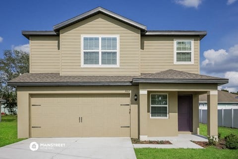 a tan house with a garage door and a driveway