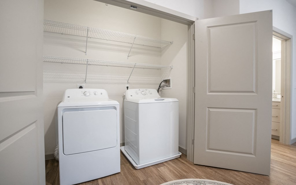 the laundry room of a home with two washers and a dryer