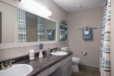 bathroom with double sinks, granite countertops, and large mirror