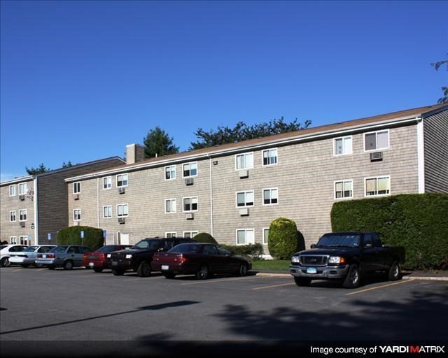 an apartment building with cars parked in a parking lot
