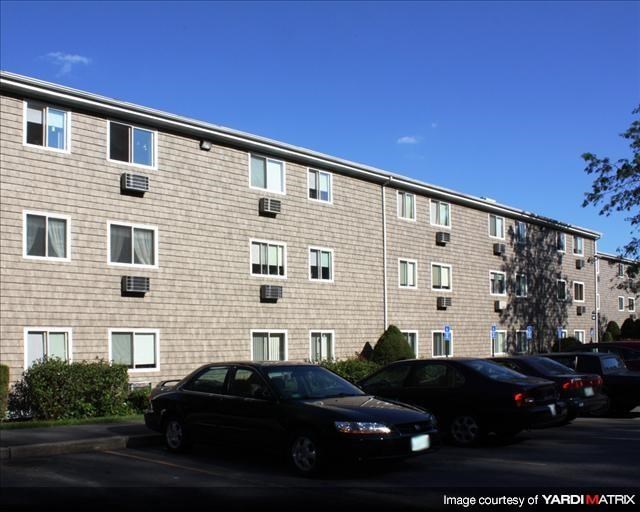 a brick apartment building with cars parked in a parking lot