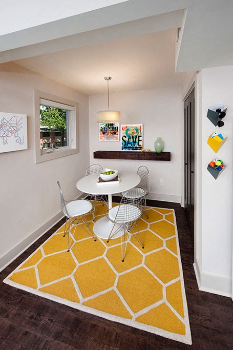 a dining room with a table and chairs and a yellow rug