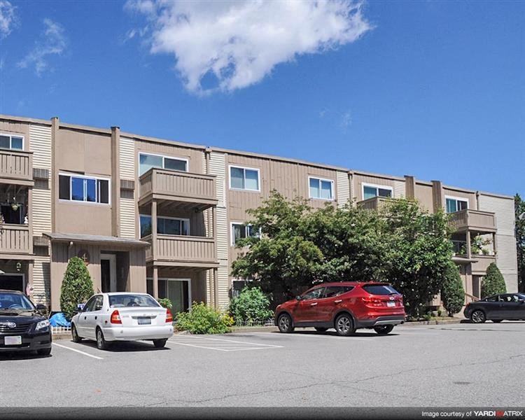 an apartment building with cars parked in a parking lot