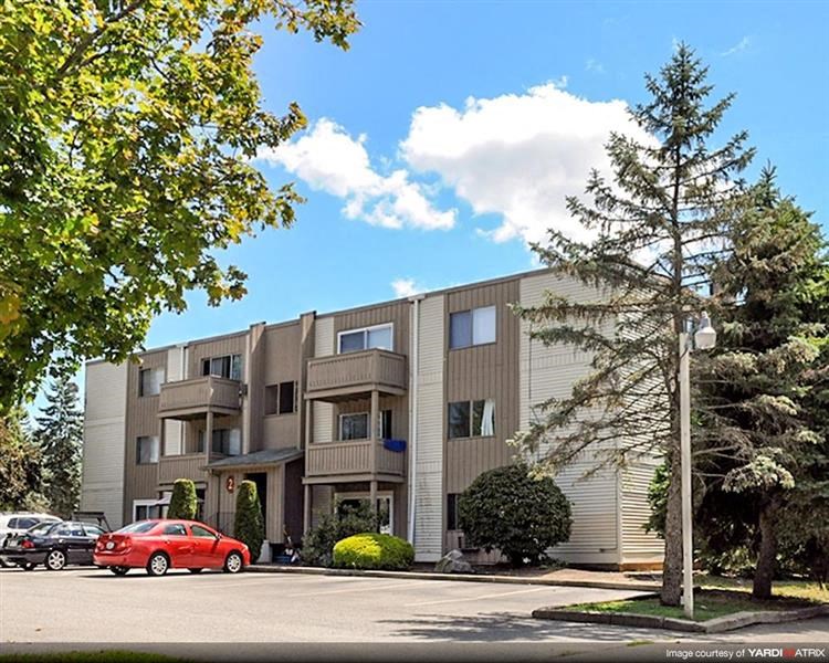 an apartment building with a red car parked in front