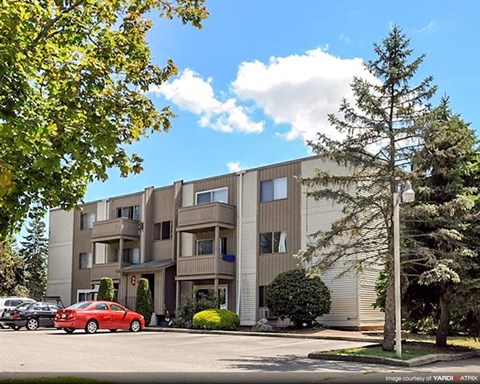 an apartment building with a red car parked in front
