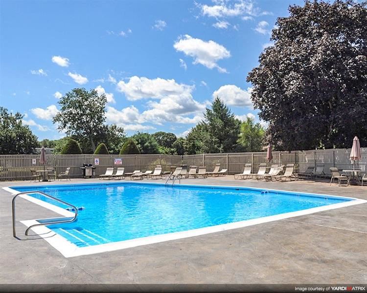 a swimming pool with chaise lounge chairs and trees in the background