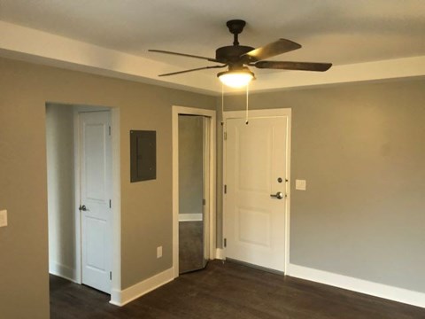 a living room with a ceiling fan and a door