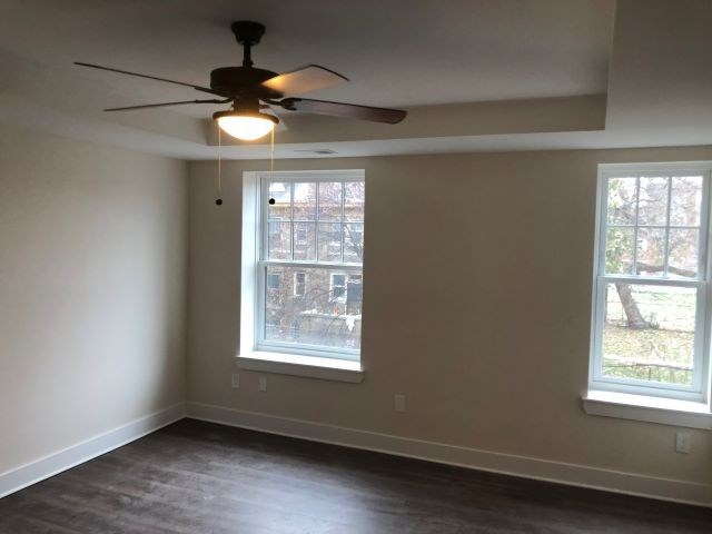 a living room with a ceiling fan and two windows