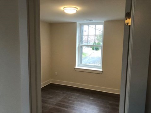 a small room with a window and wooden floors