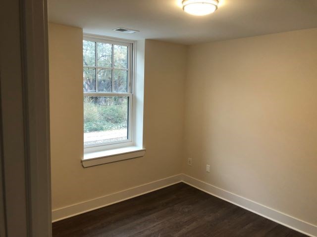 a empty room with a window and wooden floors