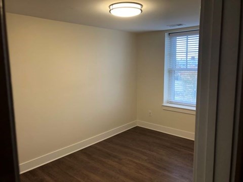an empty room with a window and a wooden floor