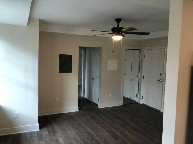 an empty living room with a ceiling fan and doors