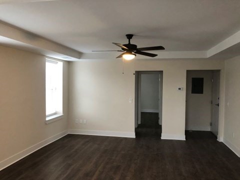 an empty living room with a ceiling fan and a door