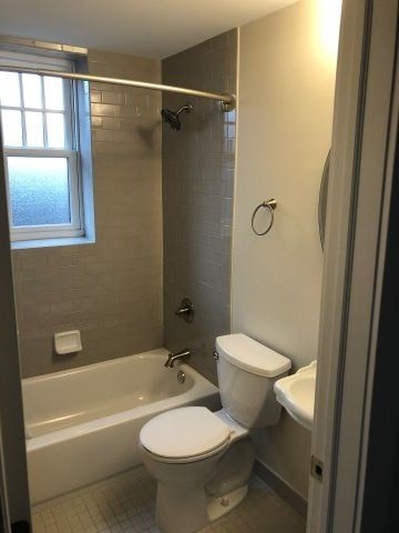 a bathroom with a toilet and a tub and a window