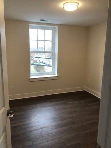 an empty room with a window and wooden floors