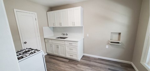A kitchen with white cabinets and a black stove top.