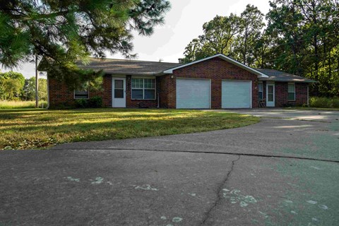 the front of a brick house with two garage doors