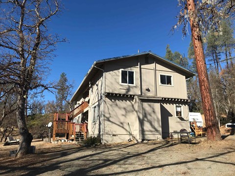 the back of the house with the deck and trees