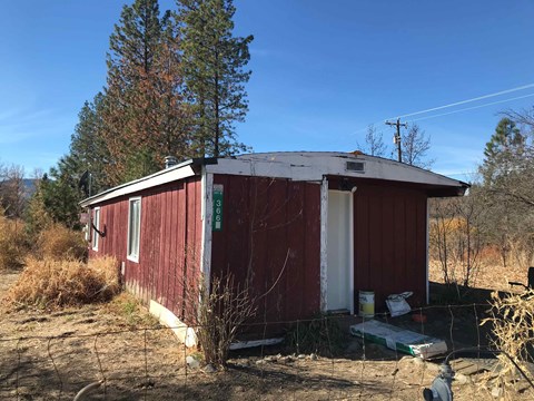 a red building with a white roof in the dirt