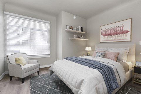 A bedroom with a bed, chair, and a painting on the wall.