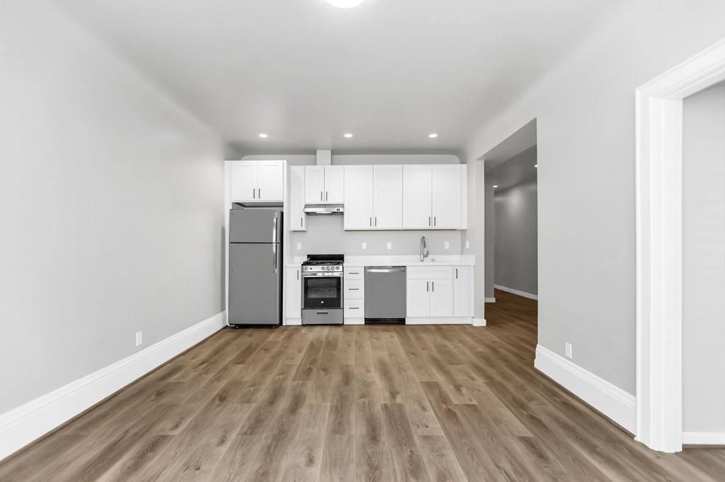 A kitchen with white cabinets and a wooden floor.