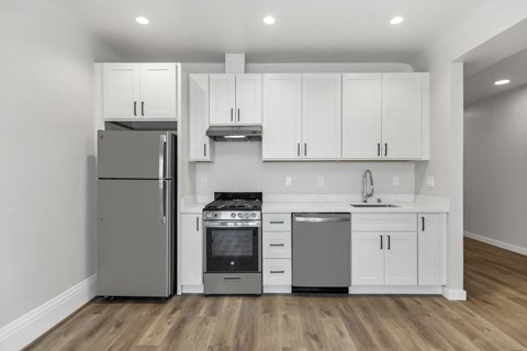 A kitchen with white cabinets and a stainless steel refrigerator.