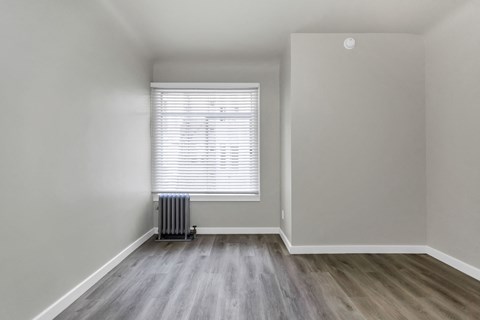 A room with a window and a radiator on the floor.