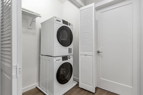 A white dryer and washer stacked on top of each other in a laundry room.