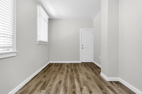 A room with a white door and wooden flooring.