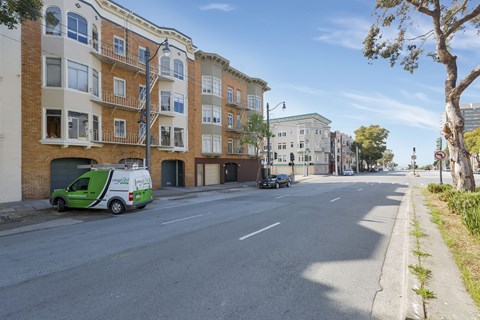 A street view with a green van parked on the side.
