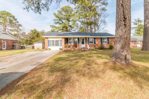 A house with a brick exterior and a large tree in front.