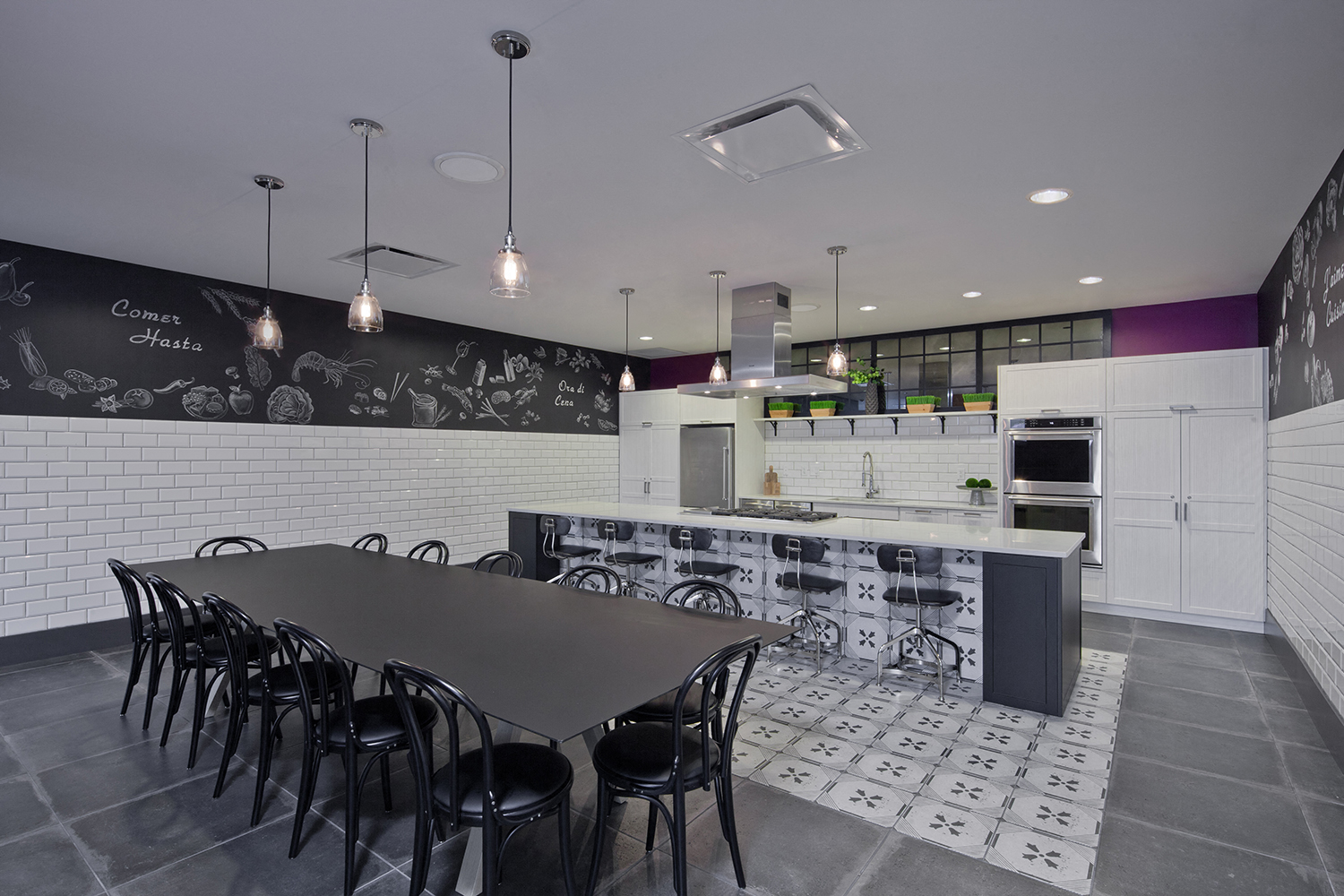 A black and white kitchen with a long table and chairs.