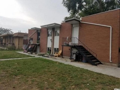 A brick building with a white door and a black staircase.