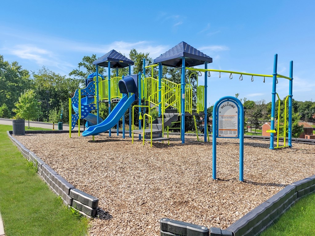 a playground with a blue and yellow playset and swing sets