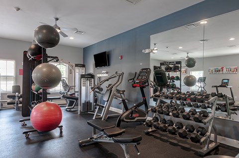 a gym with weights and balls and a large mirror