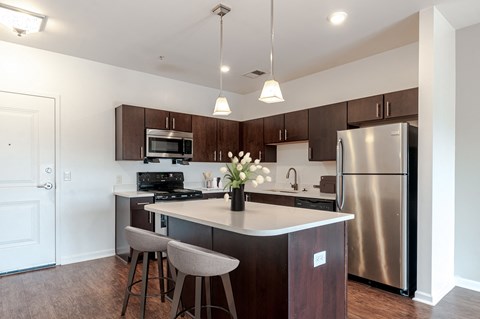 a kitchen with stainless steel appliances and a island with chairs
