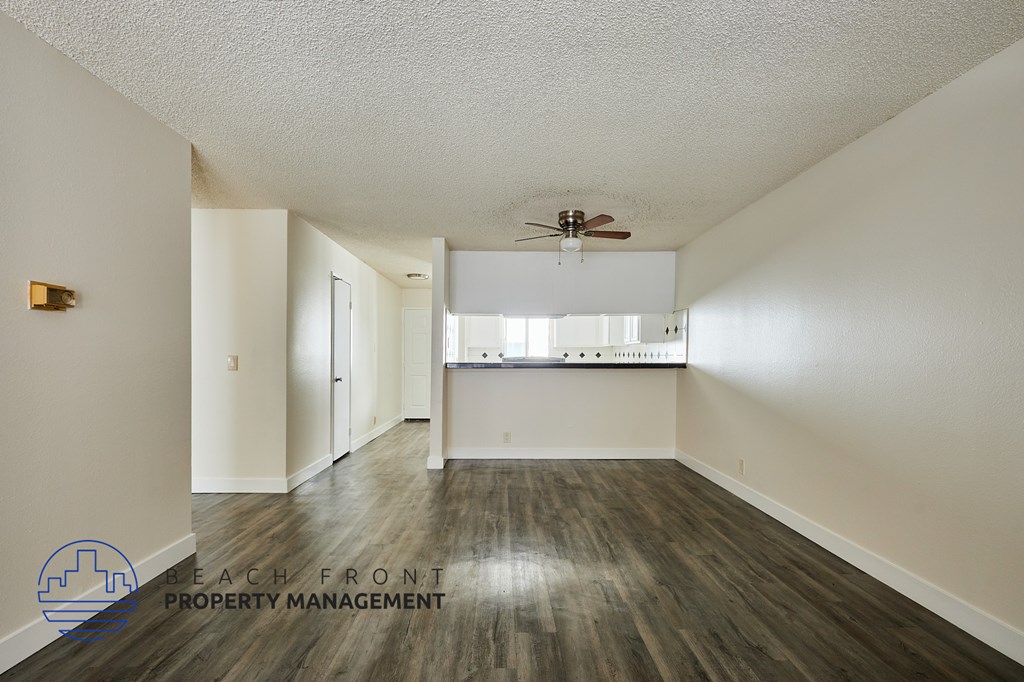 A spacious room with a ceiling fan and a logo for Beach Front Property Management.