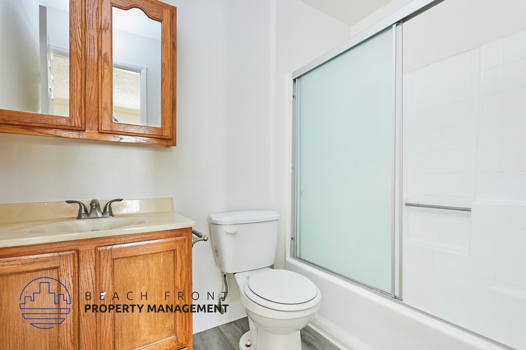 A bathroom with a toilet, sink, and mirror.