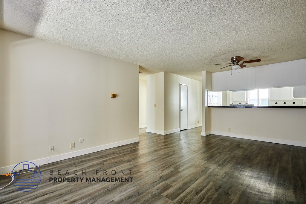 A spacious room with a ceiling fan and wooden flooring.