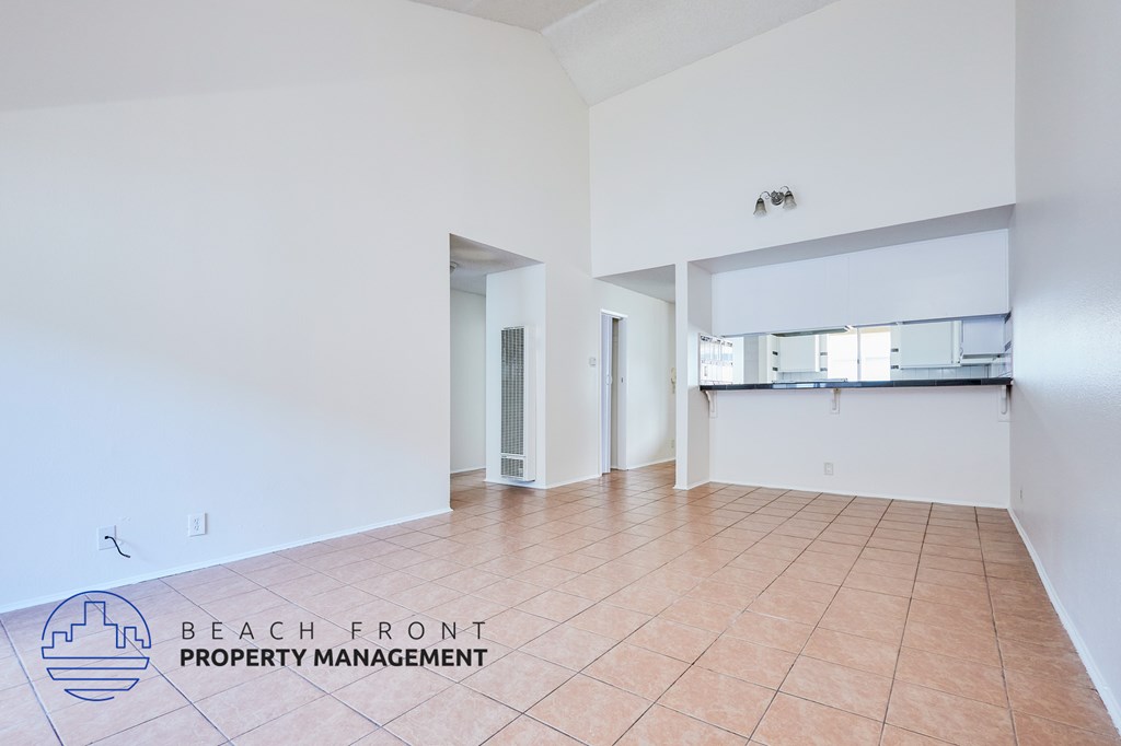 A spacious room with tiled flooring and a logo for Beach Front Property Management in the corner.