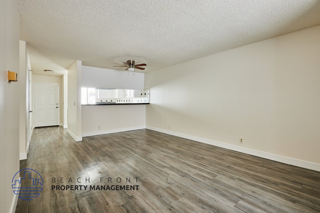 A spacious room with wooden flooring and a ceiling fan.
